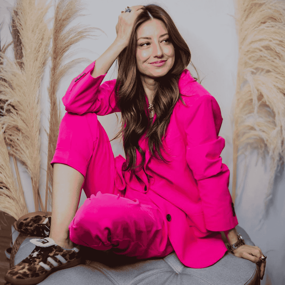 Mujer con traje fucsia sentada relajada entre pampas secas