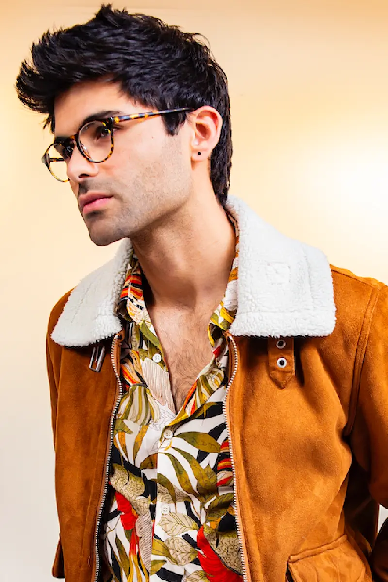 Hombre con chaqueta camel y camisa estampada tropical